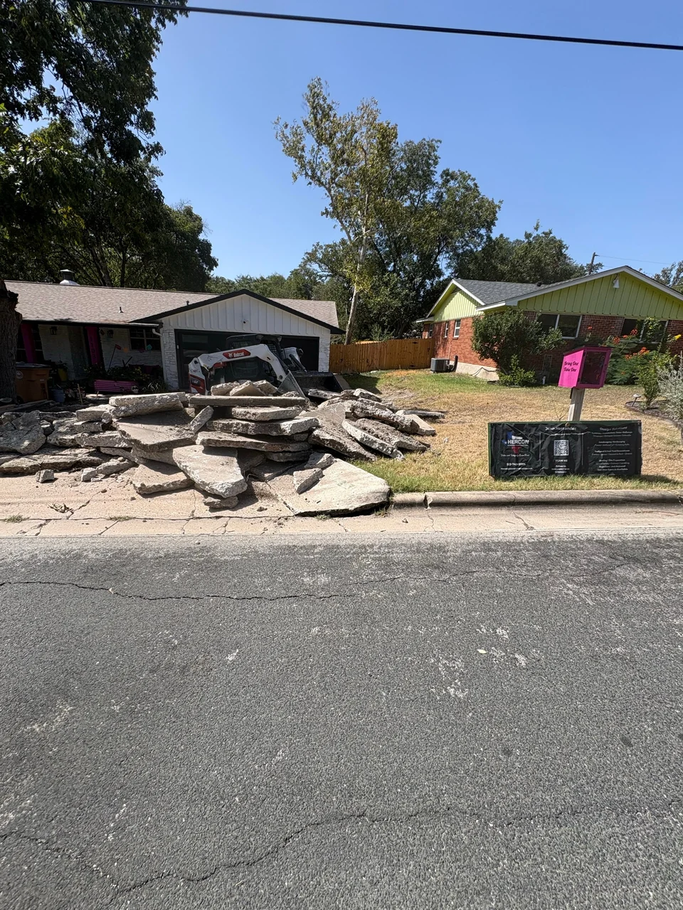 Old driveway broken out and stacked at the curb before the new pour