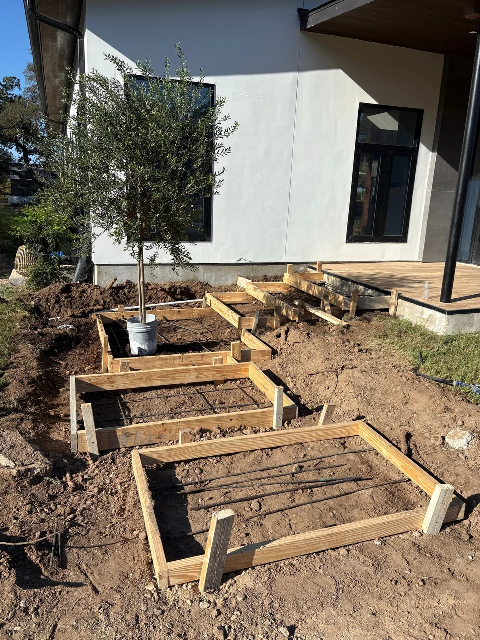 Forms and rebar set for staggered concrete steps beside a modern home in Bastrop, TX