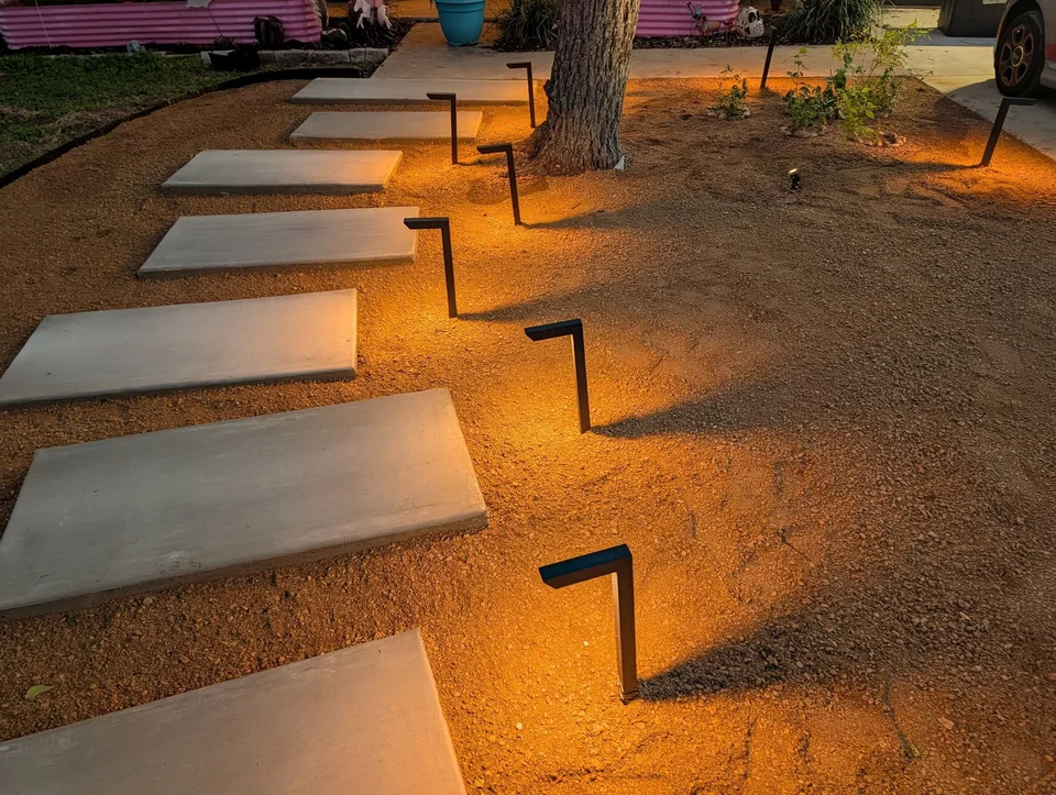 Path lights casting warm light across the crushed granite beside the steps